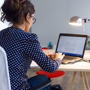 woman working on a laptop at a desk with lamp